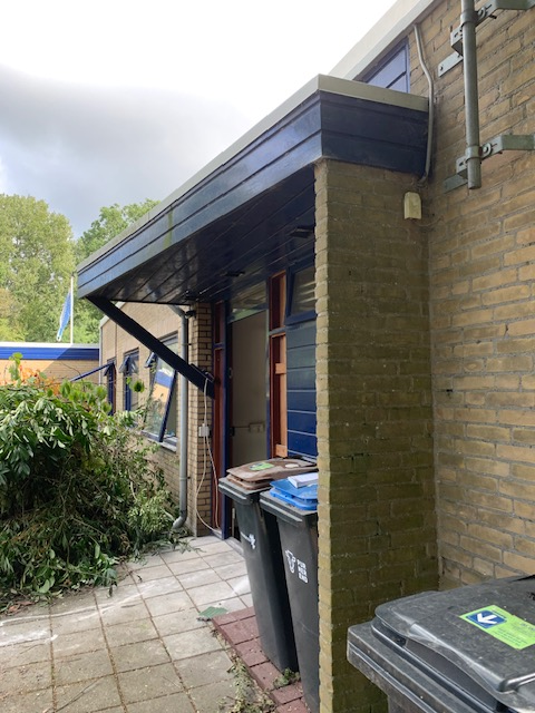 Voorgevel met een blauwe luifel boven de voordeur